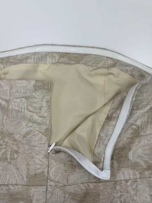 Close-up of a women's coat with beige and gray fabric, featuring a zipper and a soft inner lining, perfect for stylish winter wear.