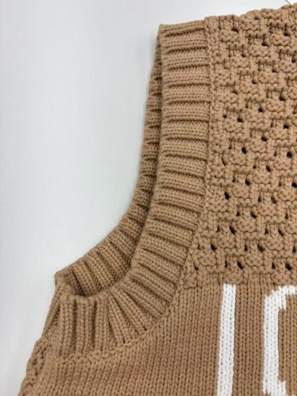 Close-up of a beige knitted sweater with intricate patterns and ribbed collar, perfect for fall fashion and cozy wear.