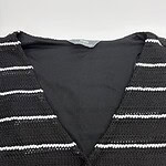 Close-up of a black and white striped knit sweater with a V-neck, suitable for casual or office wear, showcasing textured fabric and classic pattern.