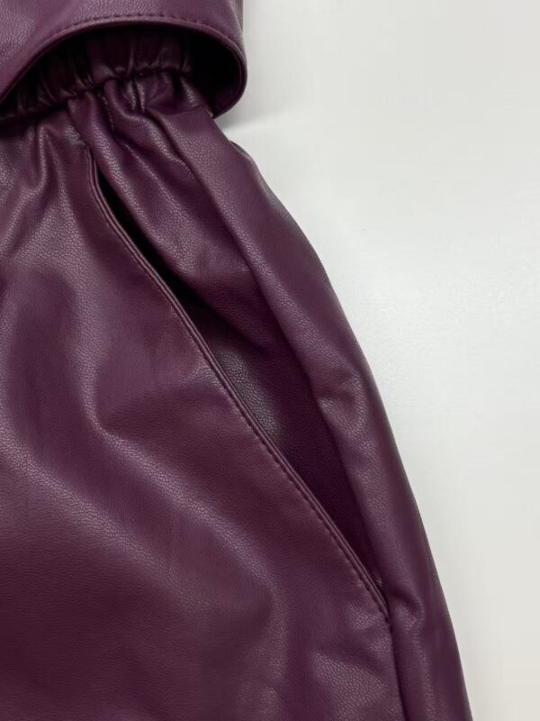 Close-up of a stylish burgundy leather skirt with a high waist and smooth texture, perfect for fashionable women's wardrobe.