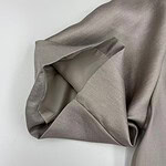 Close-up of taupe satin fabric with smooth texture and subtle sheen, ideal for luxury clothing and fashion design.