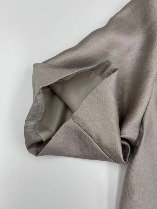 Close-up of taupe satin fabric with smooth texture and subtle sheen, ideal for luxury clothing and fashion design.