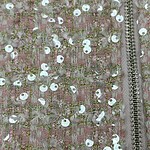 Close-up of pink fabric with intricate embroidery and shiny sequins, featuring a silver zipper on the side, suitable for fashion and couture designs.