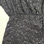 Close-up of a black dress featuring intricate beaded embellishments and a fitted waist, perfect for formal occasions.