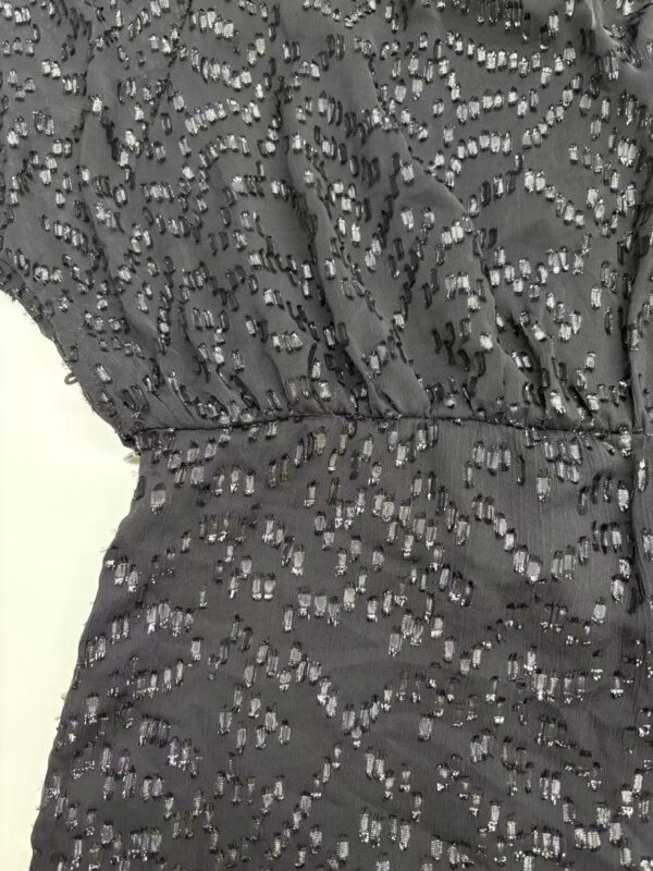 Close-up of a black dress featuring intricate beaded embellishments and a fitted waist, perfect for formal occasions.
