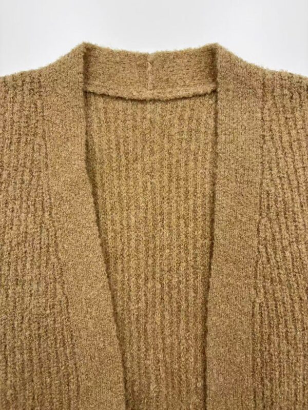 Close-up of a beige knitted cardigan with a V-neck design, showcasing textured fabric and soft material, perfect for casual or office wear.