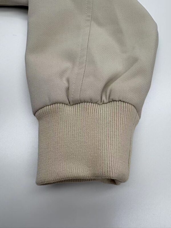 Close-up of a beige hoodie sleeve showing fabric texture and ribbed cuff, ideal for casual fashion and streetwear styles.
