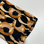 Close-up of a stylish fabric with a bold geometric pattern in black, beige, and brown, featuring an elastic cuff detail, ideal for trendy clothing or accessories.