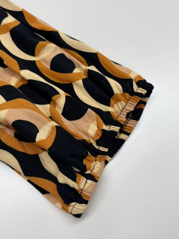 Close-up of a stylish fabric with a bold geometric pattern in black, beige, and brown, featuring an elastic cuff detail, ideal for trendy clothing or accessories.