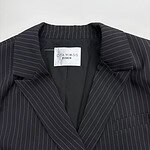 Close-up of a black pinstripe suit jacket with a notched lapel, tailored fit, and subtle white pinstripes, perfect for professional or formal occasions.
