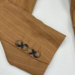 Close-up of a brown pinstripe suit sleeve with four buttons on the cuff, showcasing elegant tailoring and fabric details.