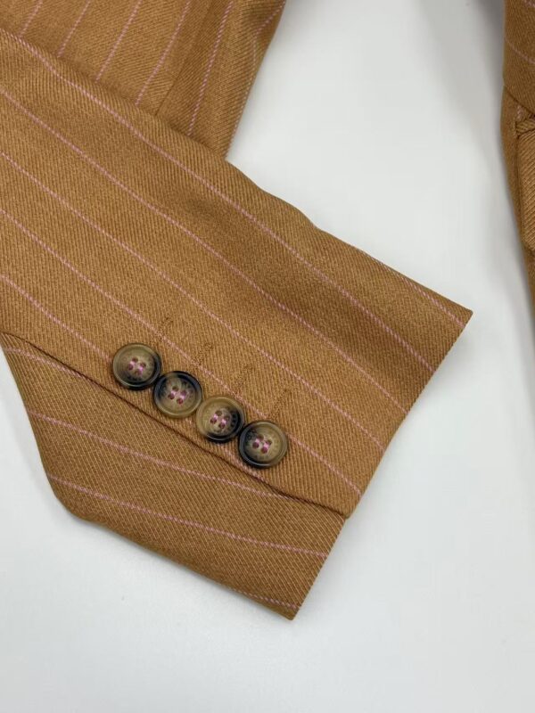 Close-up of a brown pinstripe suit sleeve with four buttons on the cuff, showcasing elegant tailoring and fabric details.