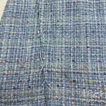 Close-up of vibrant tweed fabric with multicolored threads, showcasing texture and intricate weaving suitable for high-end fashion designs.