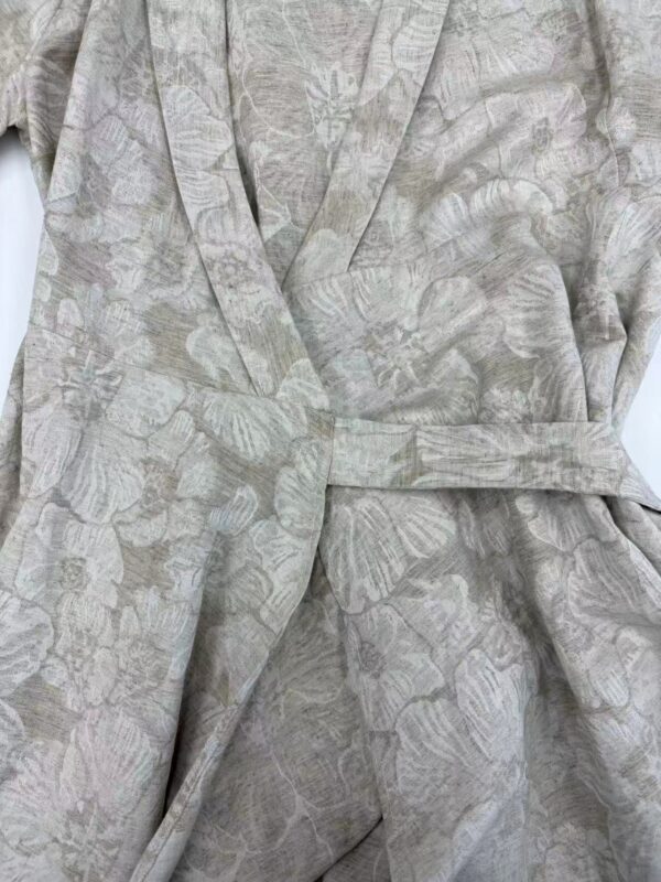 Close-up of a luxurious kimono robe with a subtle floral pattern in soft beige and pastel tones, featuring a matching belt for a sophisticated look.