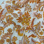 Close-up of bohemian paisley fabric with orange, yellow, and white floral patterns, showcasing detailed design and vibrant colors.