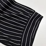 Close-up of black fabric with white vertical stripes, showing detailed texture and pattern, suitable for fashion or textile design.