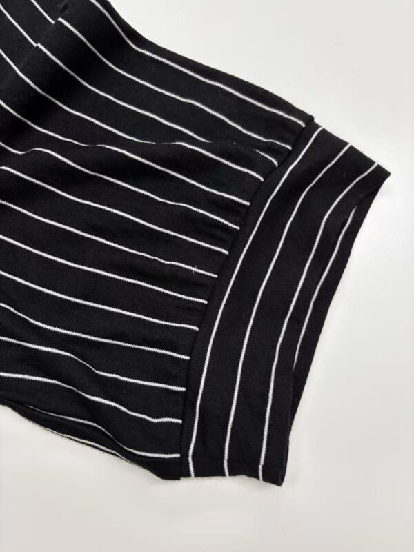 Close-up of black fabric with white vertical stripes, showing detailed texture and pattern, suitable for fashion or textile design.