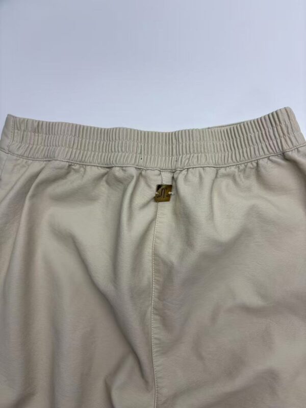 Close-up of beige casual sweatpants with elastic waistband and front zipper, suitable for comfortable everyday wear.