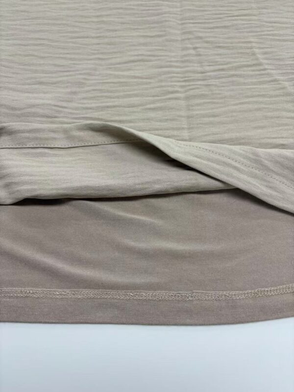 Close-up of a beige bed sheet set with smooth texture and neatly stitched edges, ideal for a stylish bedroom decor.