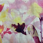 Close-up of a vibrant floral fabric with pink, yellow, and purple hues, suitable for fashion and textile design.