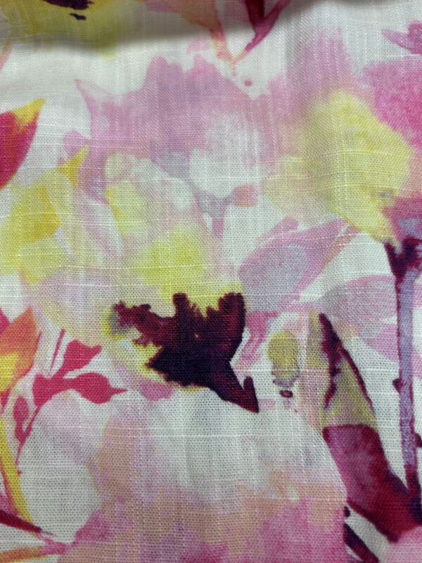 Close-up of a vibrant floral fabric with pink, yellow, and purple hues, suitable for fashion and textile design.
