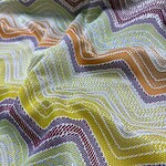 Close-up of vibrant, multicolored fabric with wavy, zigzag pattern, showcasing detailed stitching and texture, ideal for fashion and textile design.
