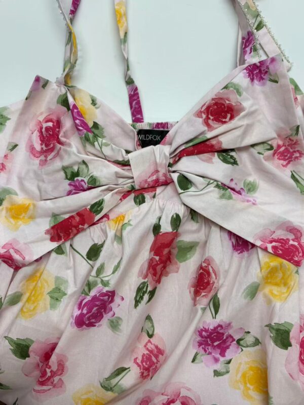Elegant floral summer dress with pink, yellow, and purple roses, featuring a large bow at the front, perfect for warm weather and outdoor events.