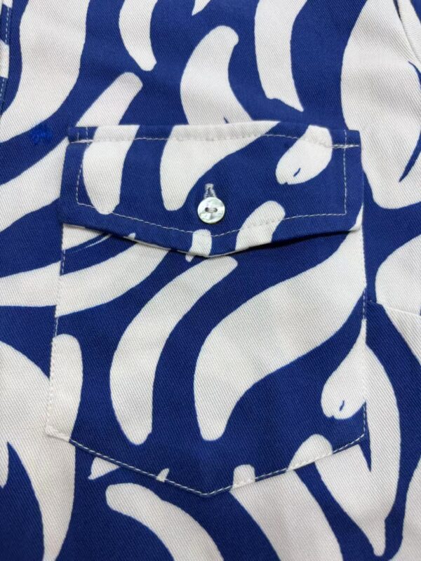Close-up of a blue and white patterned shirt with a pocket and button detail, perfect for casual or summer fashion.
