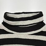 Close-up of a black and white striped turtleneck sweater, showcasing the knit texture and pattern, ideal for fall and winter fashion.