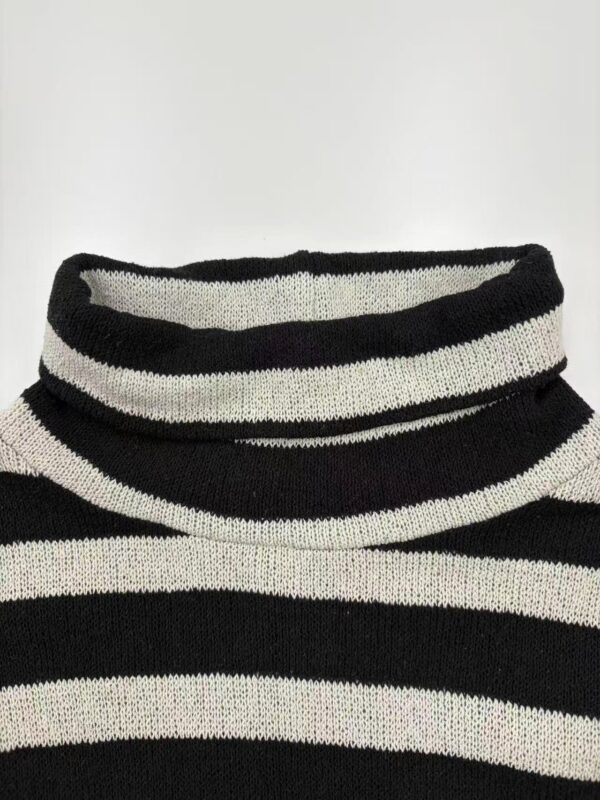Close-up of a black and white striped turtleneck sweater, showcasing the knit texture and pattern, ideal for fall and winter fashion.