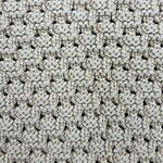 Close-up of a beige, textured knitted fabric with a detailed pattern, ideal for fashion and apparel design.