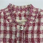 Elegant pink and white tweed jacket with textured fabric, perfect for stylish women. Features a round neckline and a decorative button closure.