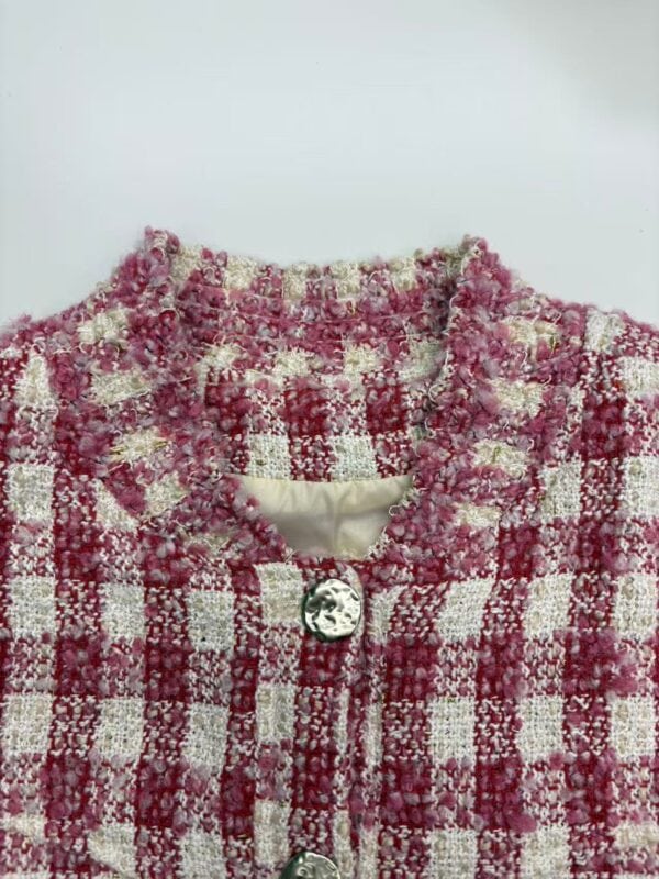 Elegant pink and white tweed jacket with textured fabric, perfect for stylish women. Features a round neckline and a decorative button closure.