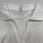 Close-up of a white ribbed polo shirt with a V-neck collar, displayed on a hanger, showcasing its soft fabric and classic design.