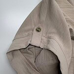 Close-up of a beige women's hoodie with a gold button detail on the shoulder, showcasing casual and stylish apparel from nbfish-fashion.com.