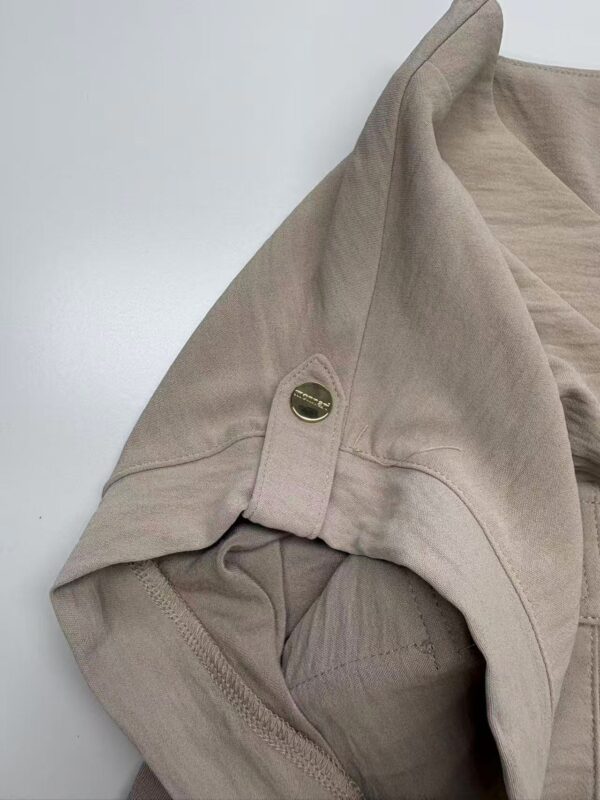 Close-up of a beige women's hoodie with a gold button detail on the shoulder, showcasing casual and stylish apparel from nbfish-fashion.com.