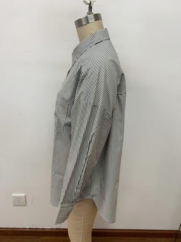 Men's long-sleeve dress shirt with vertical black and white stripes, displayed on a mannequin against a plain white wall.
