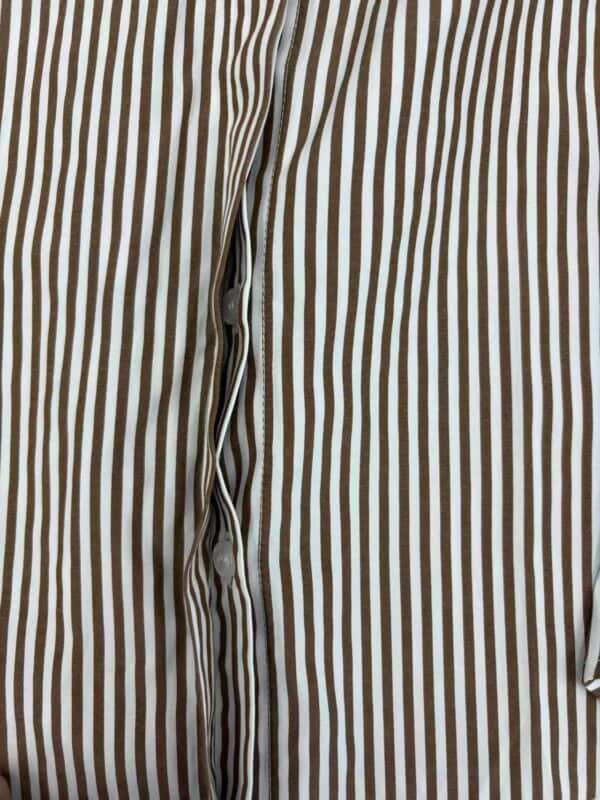 Close-up of a men's dress shirt with vertical brown and white stripes, buttoned down the front, showcasing classic formal wear style.