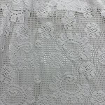 Close-up of intricate white lace fabric with floral and geometric patterns, ideal for fashion and home decor projects.