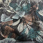 Close-up of fabric featuring a detailed leaf pattern in shades of black, white, and teal, showcasing intricate design and texture.