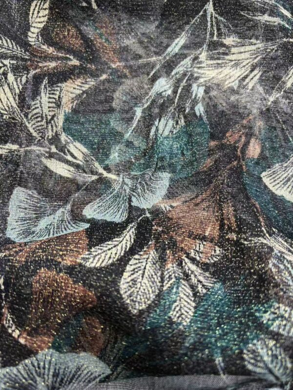 Close-up of fabric featuring a detailed leaf pattern in shades of black, white, and teal, showcasing intricate design and texture.
