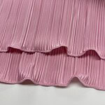 Close-up of pink pleated fabric with wavy ruffle edges, ideal for fashion and clothing design projects.