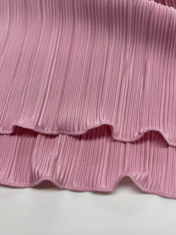 Close-up of pink pleated fabric with wavy ruffle edges, ideal for fashion and clothing design projects.