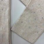 Close-up of beige knit fabric with small, colorful beads for luxury fashion design.