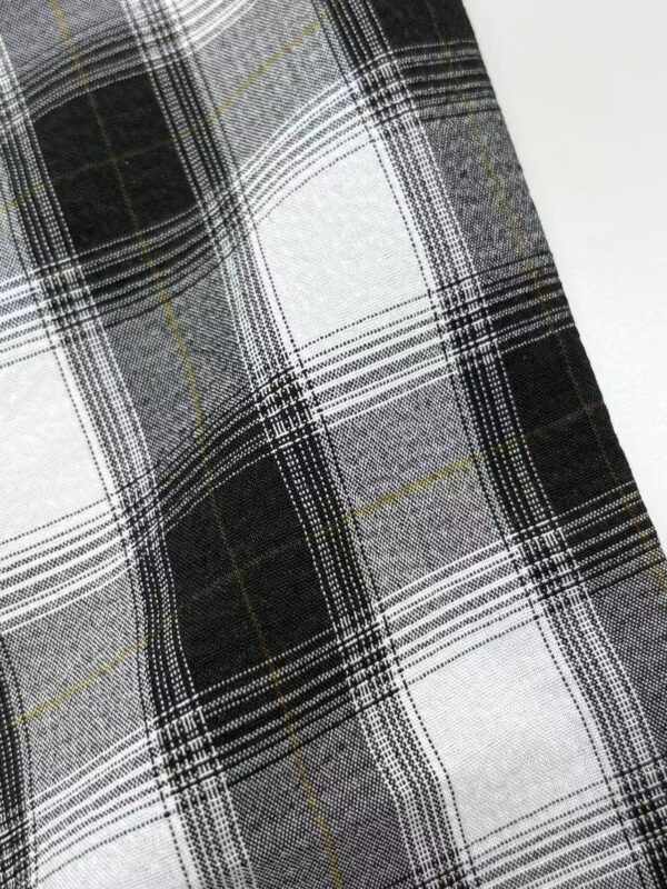 Close-up of black and white plaid fabric with yellow accents, ideal for fashion and clothing design.