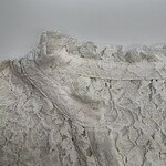 Close-up of white chalk cliffs with detailed surface texture and natural formations, under a cloudy sky.