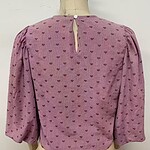 Pink blouse with small heart patterns, puffed sleeves, and a keyhole back button for stylish women's fashion.
