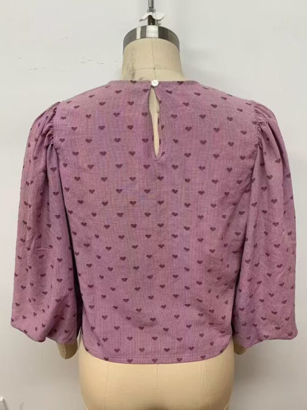 Pink blouse with small heart patterns, puffed sleeves, and a keyhole back button for stylish women's fashion.