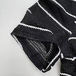 Close-up of a black and white striped knitted sweater with textured pattern and detailed stitching.
