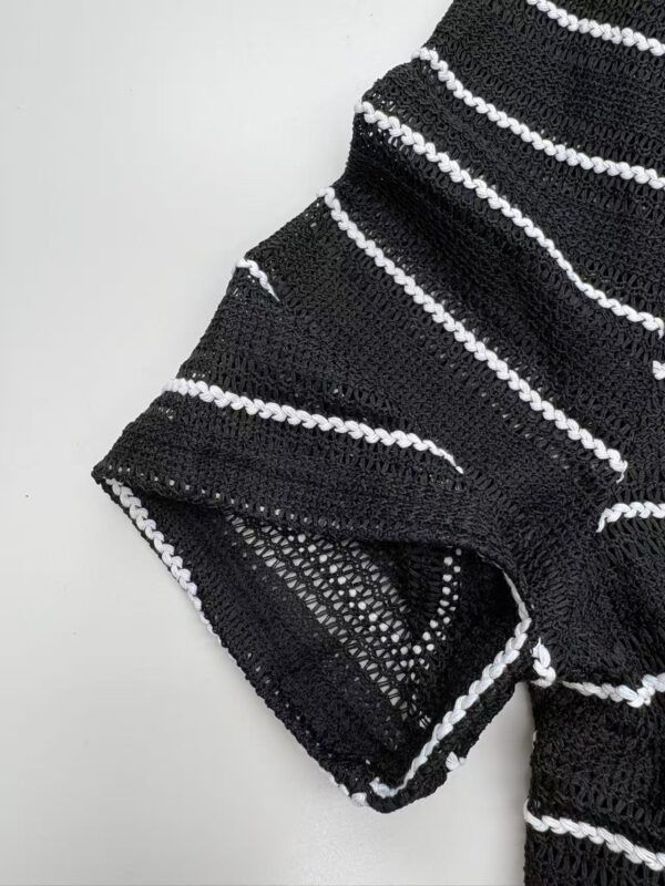 Close-up of a black and white striped knitted sweater with textured pattern and detailed stitching.